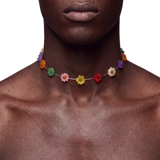 A close-up of a shirtless man wearing a colorful beaded choker necklace with small flower-like beads in red, orange, yellow, green, pink, and purple, against a plain white background.